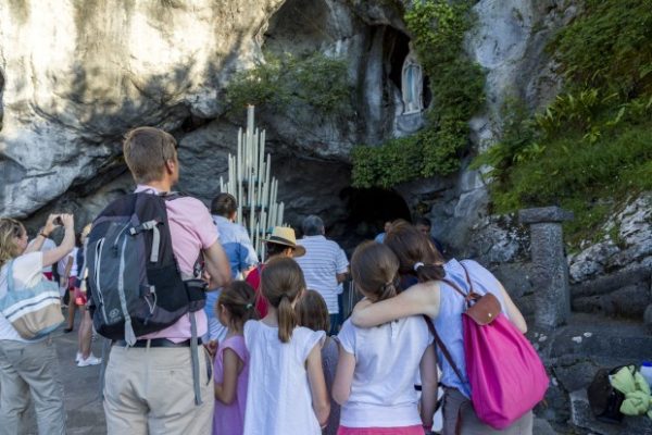 Devotos en la Gruta del Santuario de Nuestra Señora de Lourdes en Francia, orando y velando la imagen de la Virgen María | María por el Mundo